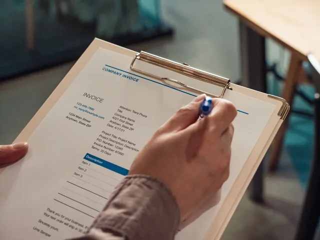 Person's hand holding a company invoice on a clipboard with a pen. Vilka verifikationer krävs för att bokföringen ska vara god?